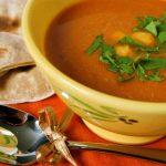 Spicy Chickpea Soup recipe served in yellow bowl with chapattis in background