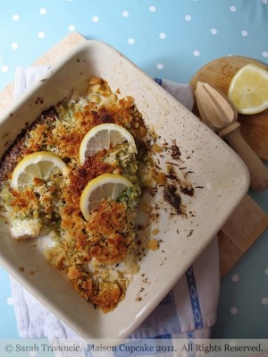 Baked fish with pesto covered with lemon slices.