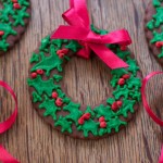 Christmas Wreath Cookie decorated with green holly and red berry icing. A red ribbon bow to decorate or hang them on a Christmas Tree.
