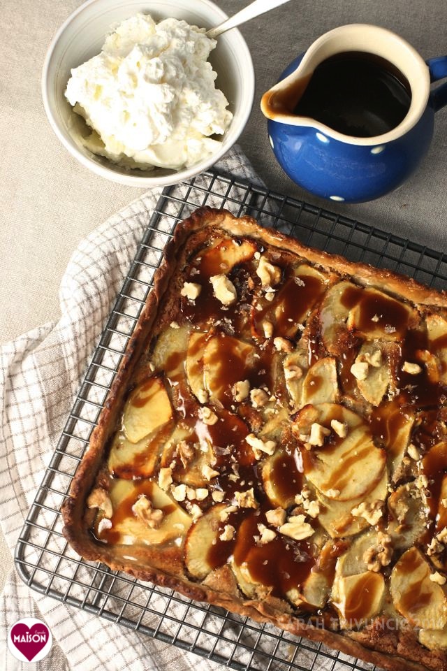 Toffee Apple Tart; rectangular pastry tart with apple slices and caramel sauce. A jug of sauce and bowl of whipped cream lie in the background.