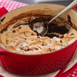 Nutella Semolina Meringue Pudding in an oval shaped red casserole dish, on a red gingham cloth