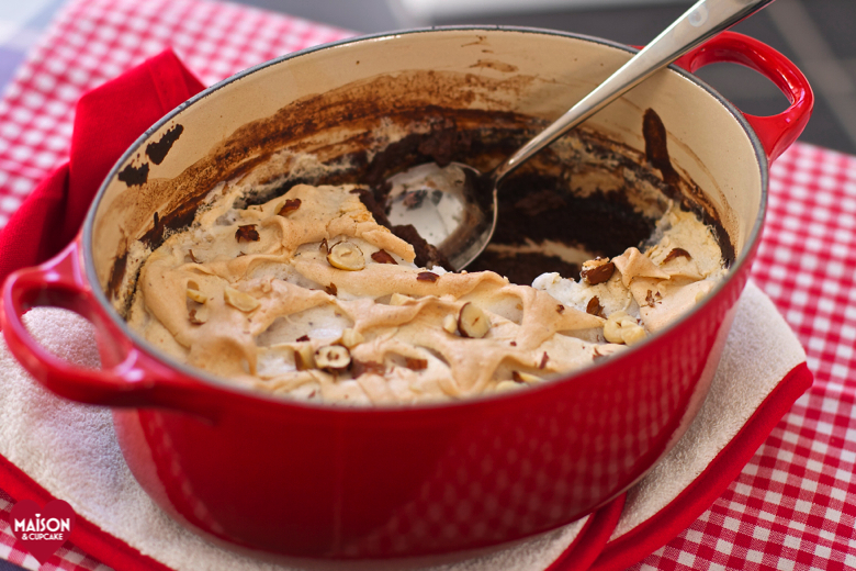 Nutella Semolina Meringue Pudding in an oval shaped red casserole dish, on a red gingham cloth.